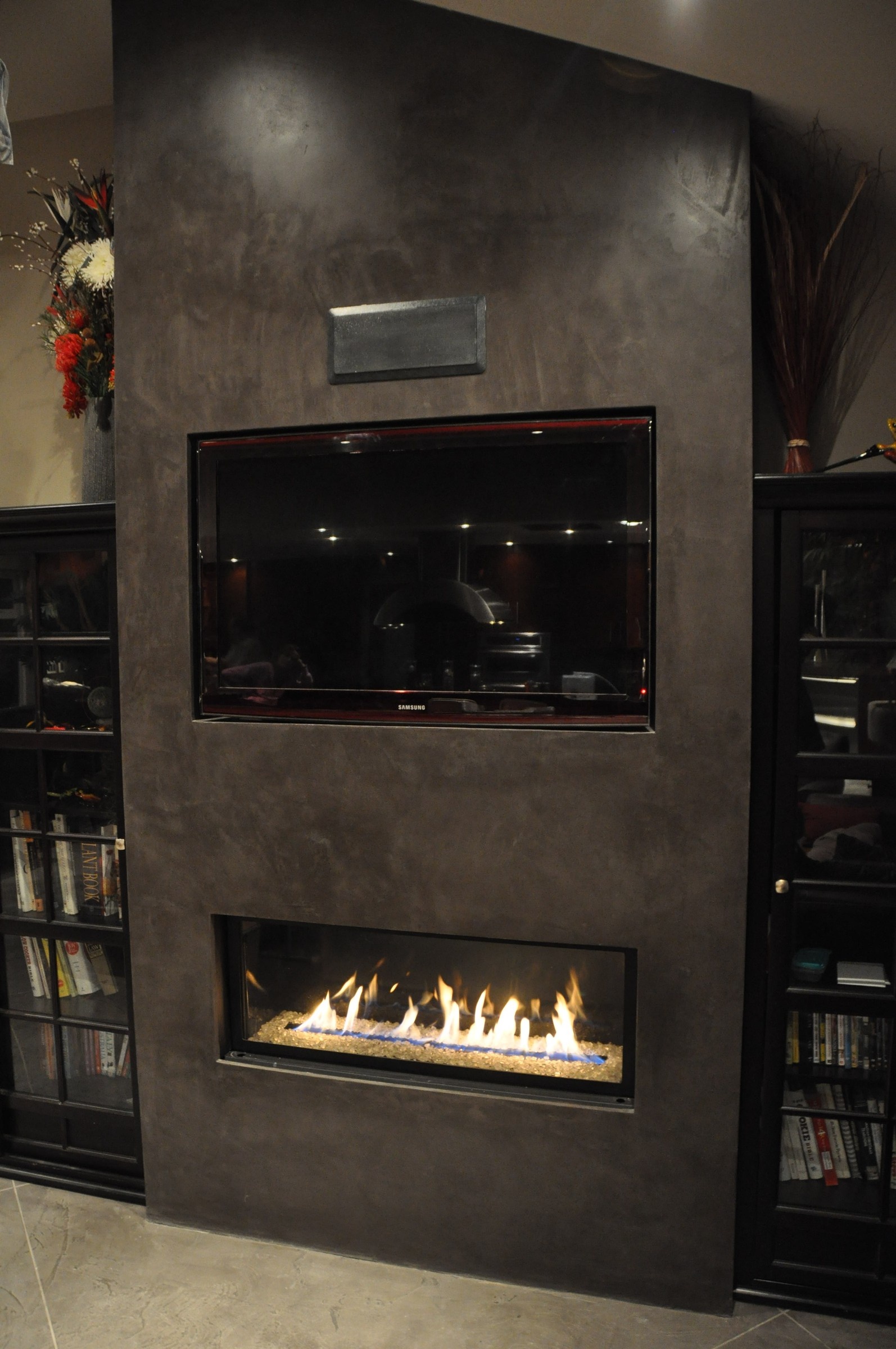 Dark charcoal StoneCraft media wall with blazing linear fireplace