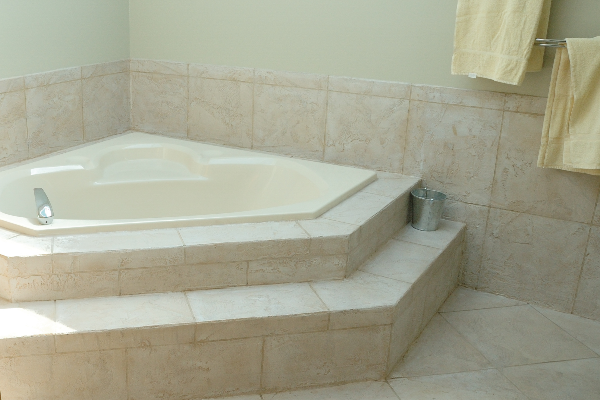 Bathroom with cream StoneCraft corner tub surround and wall panels