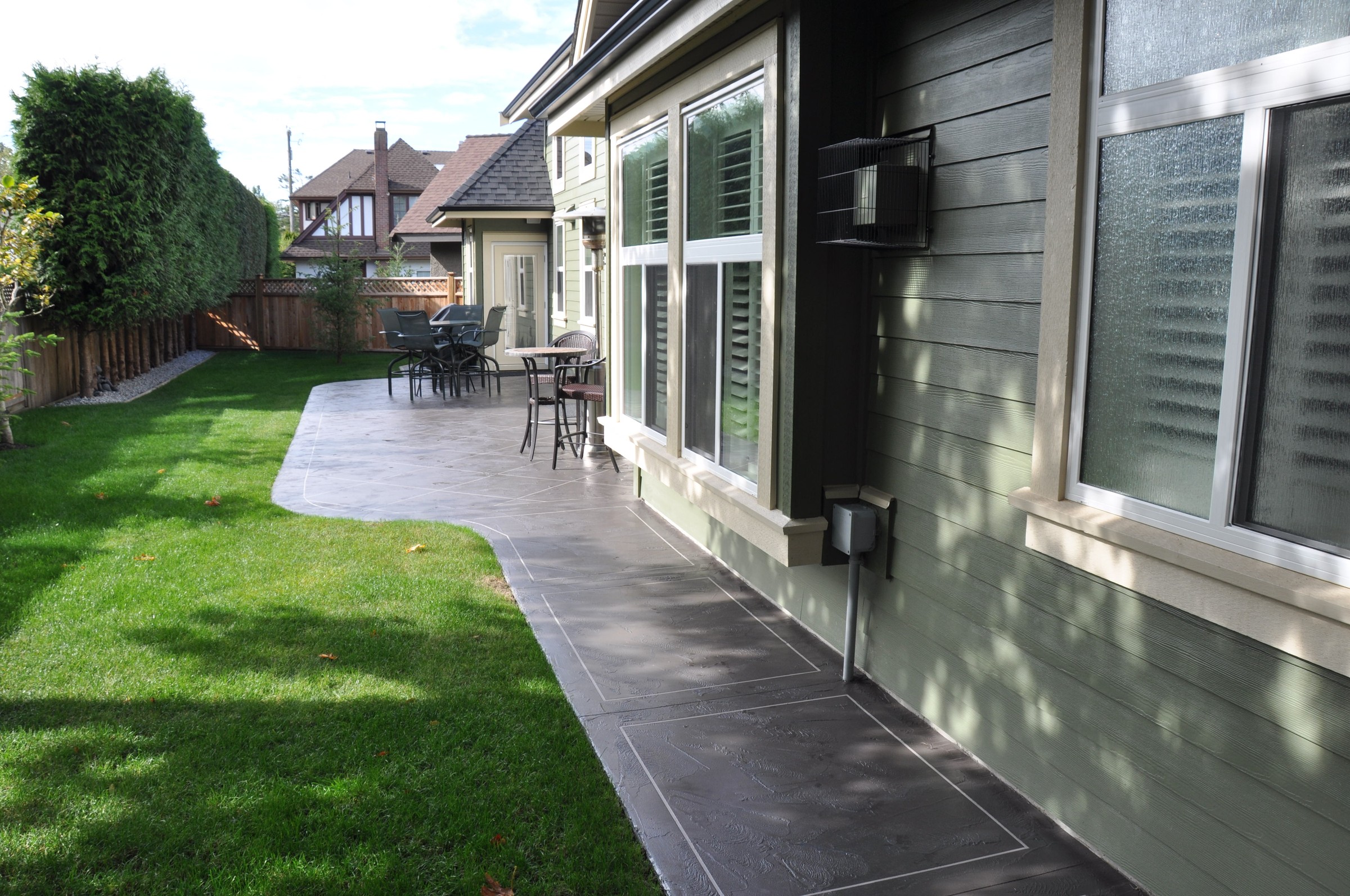 Ground-level StoneCraft waterproofed patio with dining area adjacent to house